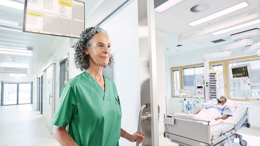 Nurse enters ICU patient room with prioritized alarm handling