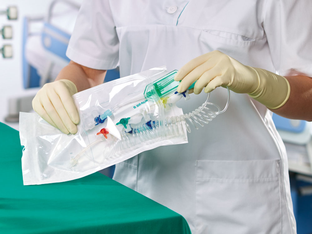 Healthcare worker wearing gloves unwrapping sterile spiral line set for infusion